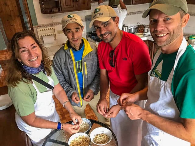 Four people in casual wear and aprons are standing around a table, smiling while preparing food in a kitchen. Two bowls of beans from Ecuador are on the table.