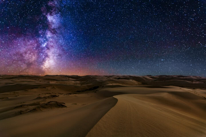 A vast desert landscape in Mongolia under a clear, star-filled night sky with the Milky Way galaxy visible above.