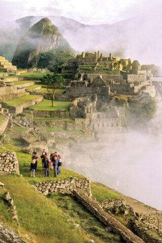 Group of tourists standing in Incan ruins of Machu Picchu at the UNESCO World Heritage site near Sacred Valley Peru