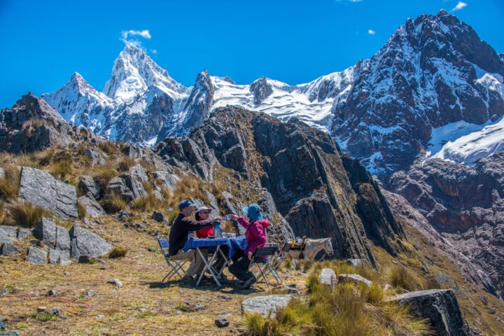 Hikers dining at a table with mountain views in Cordillera Blanca mountain range in Peru.