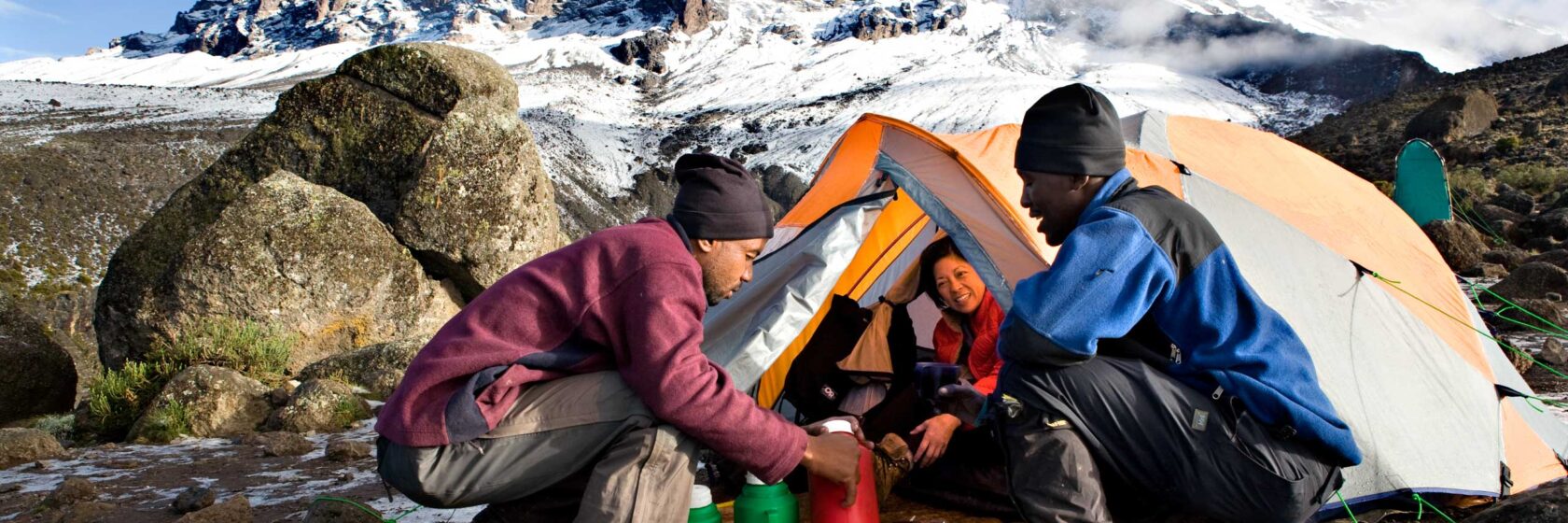 Three travelers at a campsite in Kilimanjaro.
